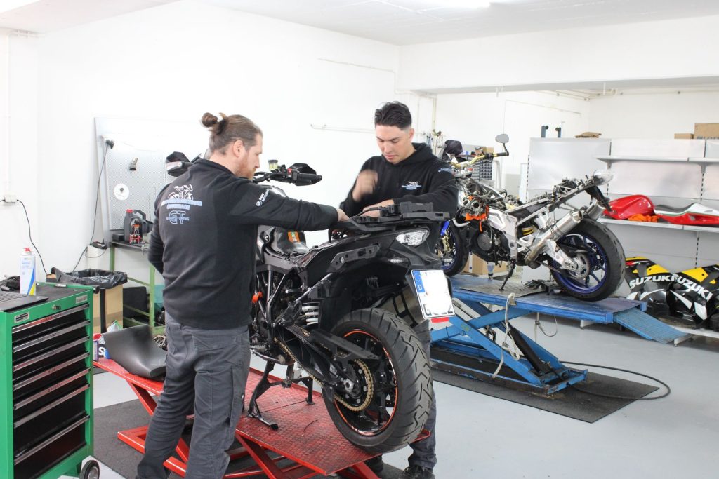 Zwei Mechaniker arbeiten an Motorrad