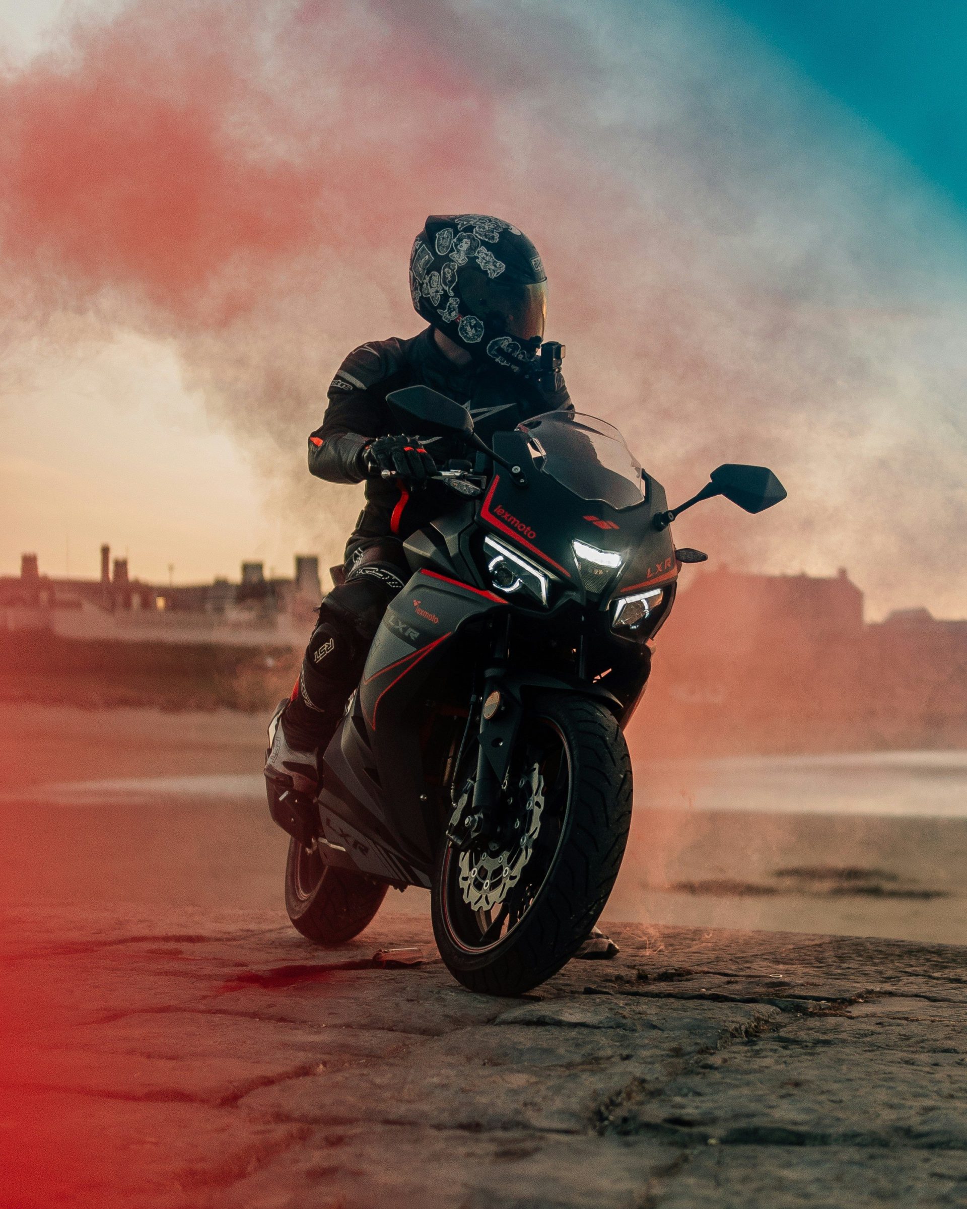 Mann mit schwarzem Motorradhelm fährt tagsüber auf einem braunen Feldweg Motorrad.